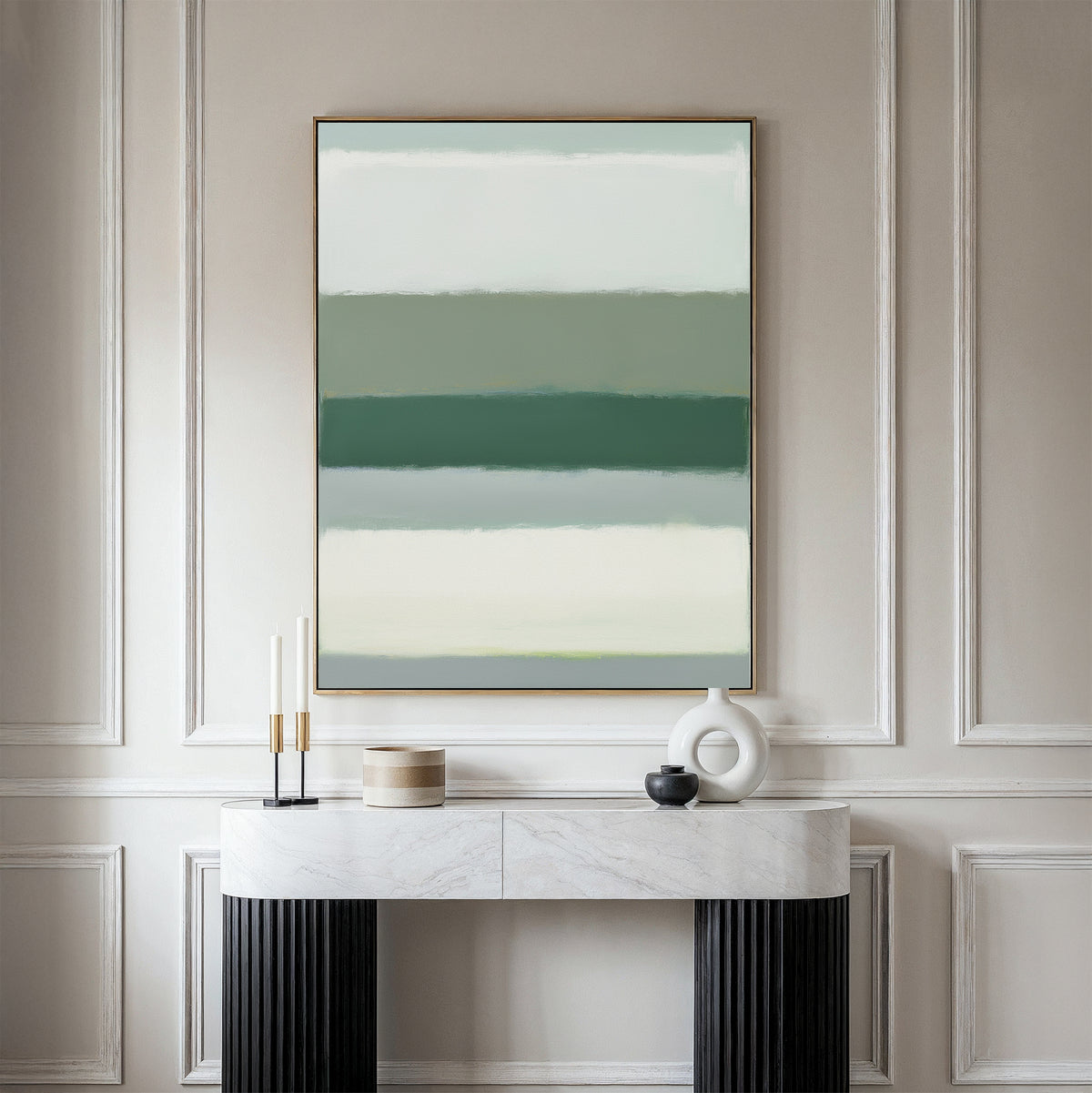 A modern console table with black legs and a white marble top displays minimal decor like candles and vases. Above it hangs the Sage Gradient Canvas Art - Vertical, featuring calming green and beige stripes on a pale wall.