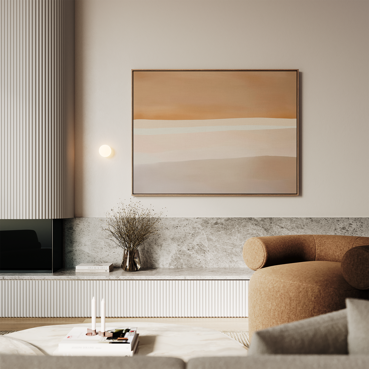 A modern living room with neutral tones, featuring a tan curved sofa, a low marble shelf with a vase of dried branches, the Saharan Lines Abstract Canvas Art in beige and peach on the wall, and candles with stacked books on the coffee table.