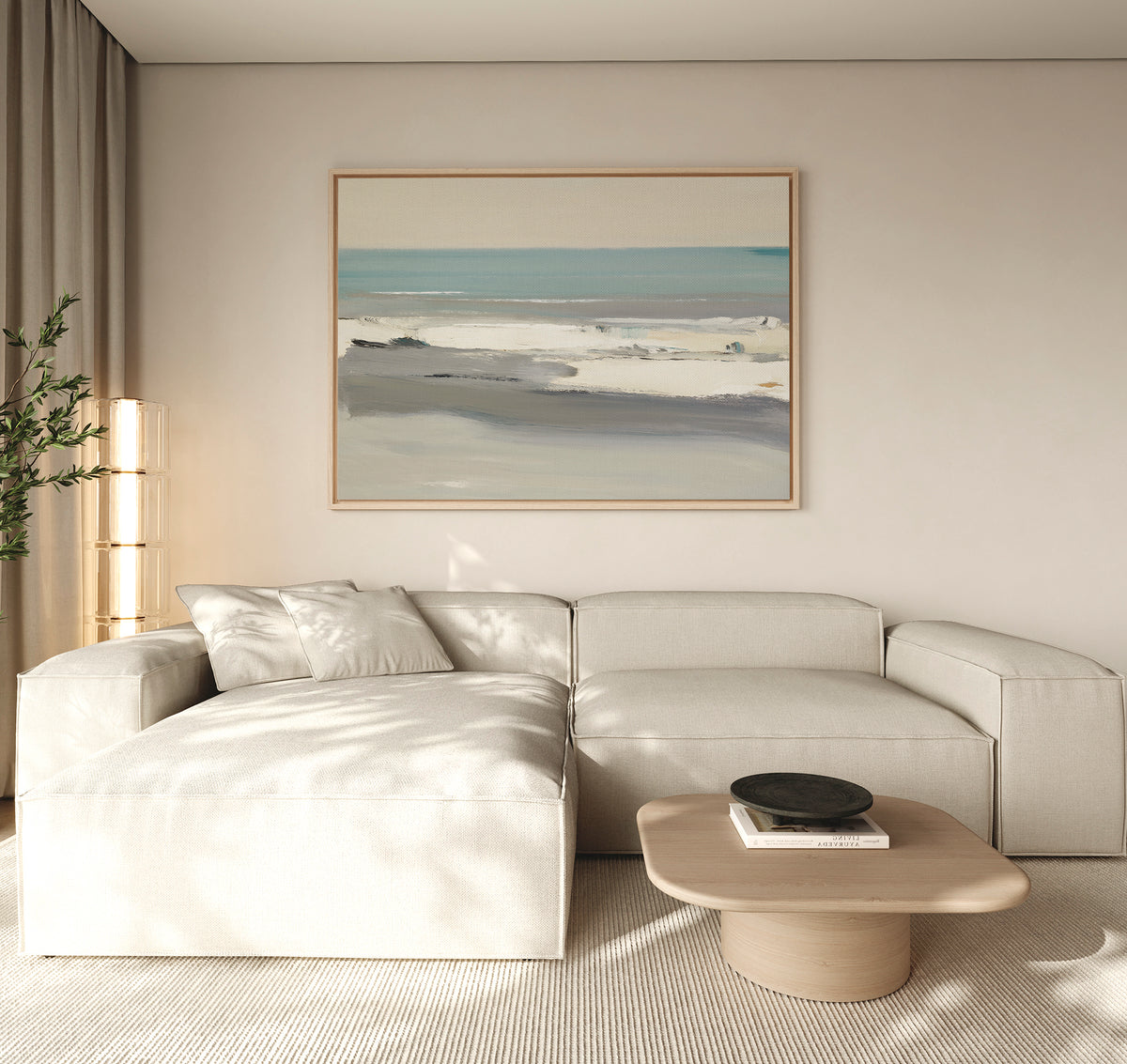 A modern living room features a beige sectional sofa, light wood coffee table, and the Sandy Retreat Canvas Art - Horizontal above. Soft natural light fills the space, with a green plant in the corner enhancing calming coastal vibes.