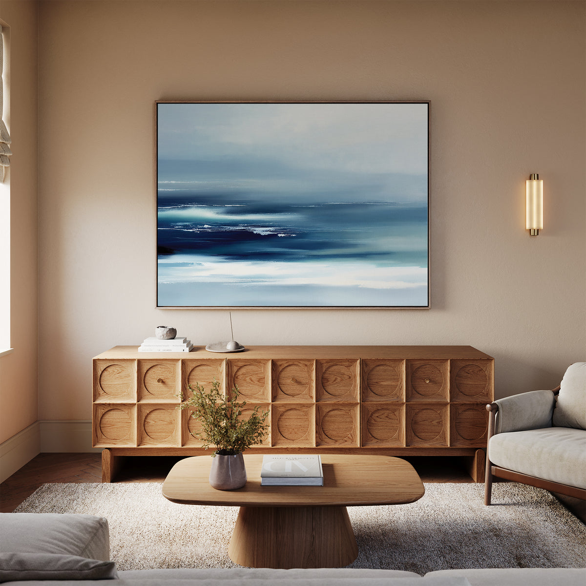 A modern living room with a light beige sofa, wooden coffee table, and sideboard, highlighted by the Sapphire Current Canvas Art - Horizontal as serene wall art. A wall sconce and flower vase finish this Nordic Park-inspired space.