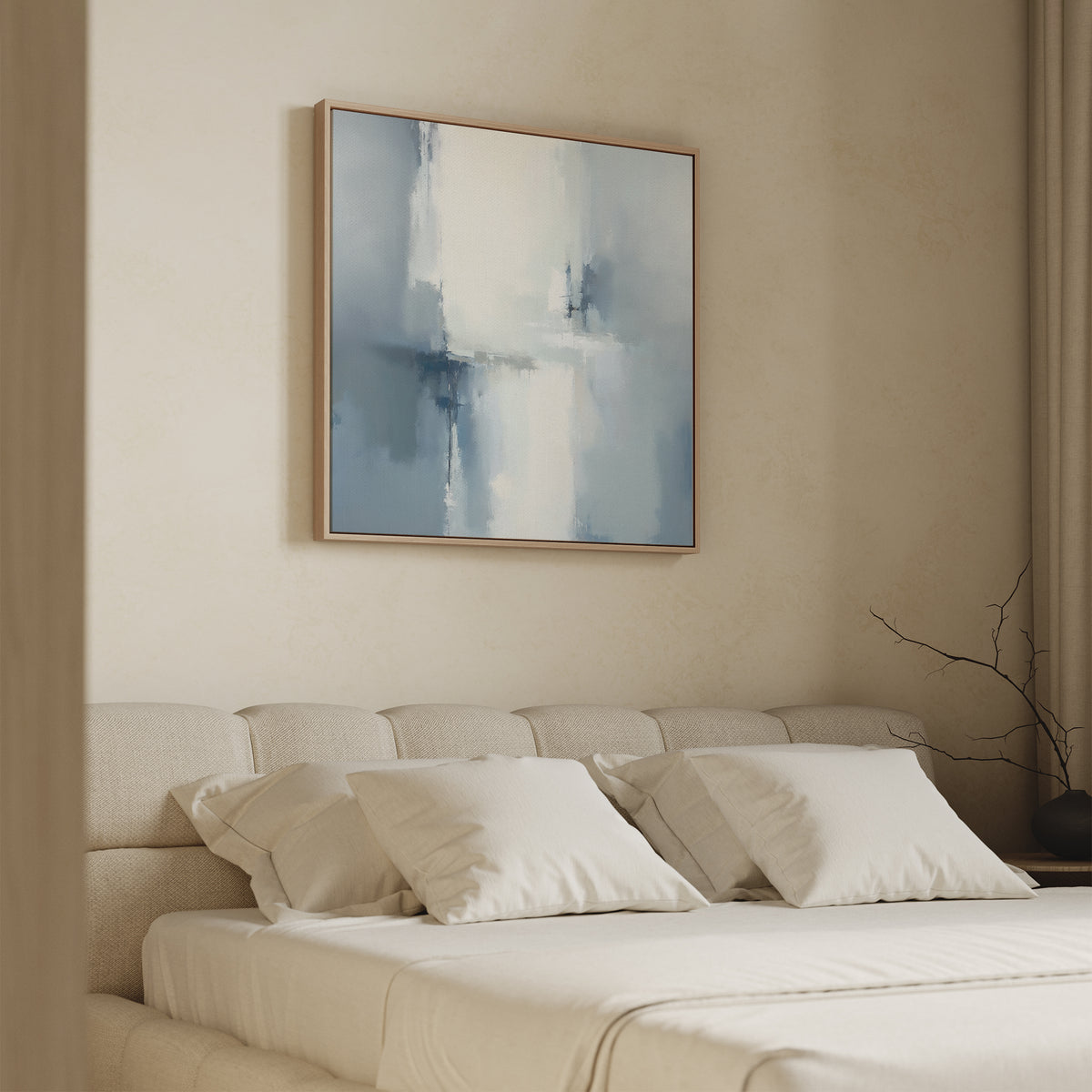 A minimalist bedroom features a cream upholstered bed with white pillows. Above the bed, the Silver Cross Formation Canvas Art - Square in soft blue and white tones creates a serene focal point. A dark vase with bare branches sits on the nightstand.