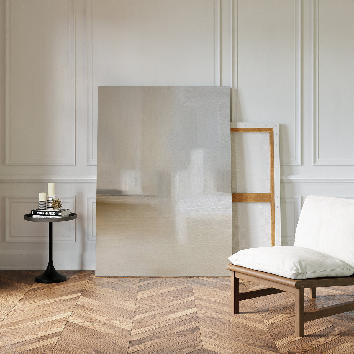 A modern, minimal living space features a cushioned wooden chair, candles and books on a round black side table, with the Soft Layers Canvas Art - Vertical leaning against a white paneled wall on herringbone wood floors.