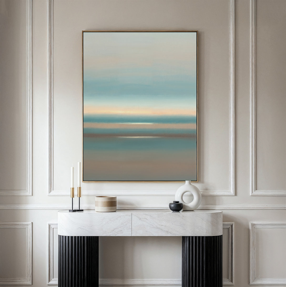 A minimalist room features a marble console table with decor accents and the Soft Tide Layers Canvas Art - Vertical, showcasing calming blue, beige, and peach hues on a light-paneled wall—perfect for tranquil home decor.