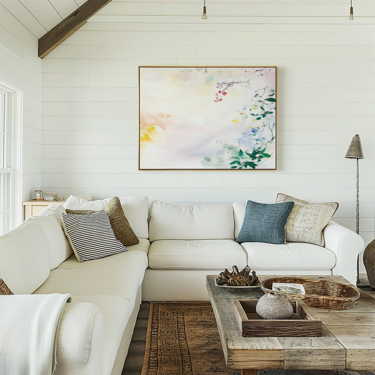A cozy living room with a white sectional sofa, assorted pillows, a rustic wooden coffee table, woven accents, and soft floral decor highlighted by the Spring Reverie Canvas Art - Horizontal on white shiplap walls.