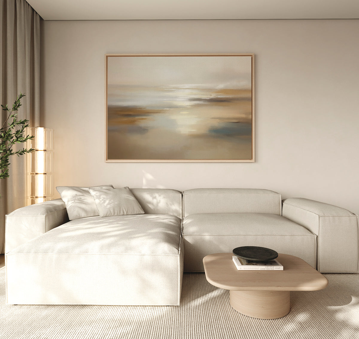A minimalist living room features a light beige sectional sofa, a wooden coffee table with a black bowl, a tall lamp, and "Sunlit Waters Canvas Art - Horizontal" above the sofa. Neutral tones enhance the calm atmosphere.