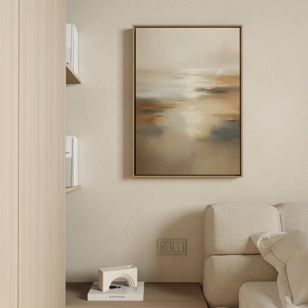 A beige, minimalist living room corner with a white textured sofa, a shelf with books, a geometric decor piece, and the Sunlit Waters Canvas Art - Vertical in warm neutral tones displayed on the wall.