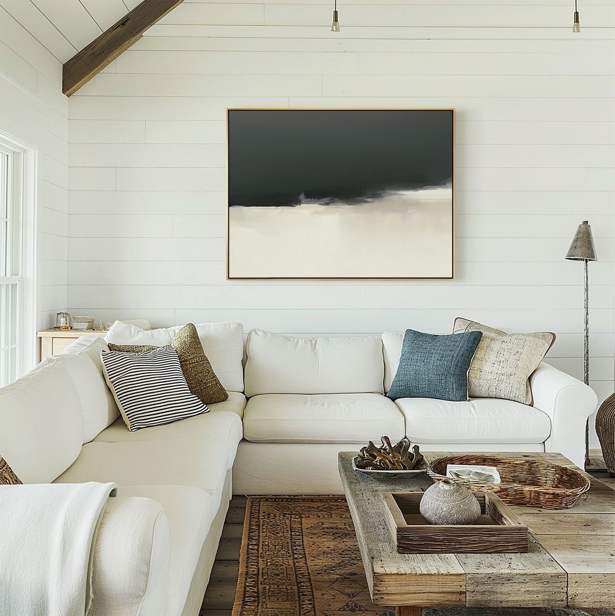 A cozy living room with a white sectional sofa, assorted throw pillows, a wooden coffee table with decor, and the Tempest Brewing Canvas Art - Horizontal displayed on a white shiplap wall beneath streaming natural light.