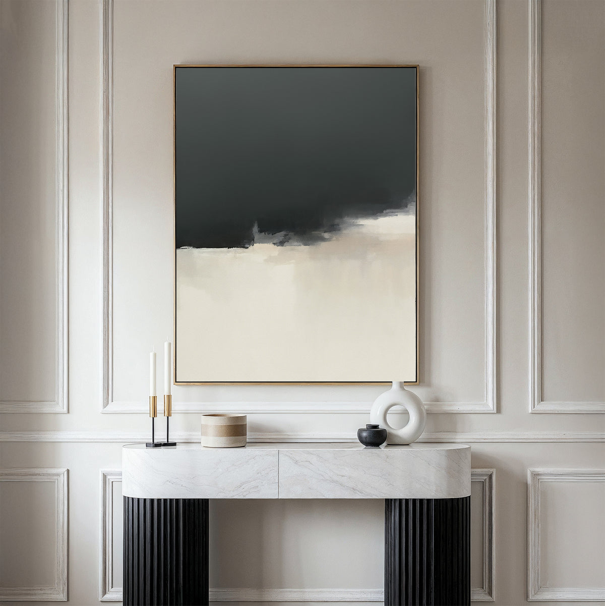 A minimalist console table with decorative objects rests against a beige wall, featuring Tempest Brewing Canvas Art - Vertical, an atmospheric piece in dark gray, cream, and beige hues for a modern, elegant interior.