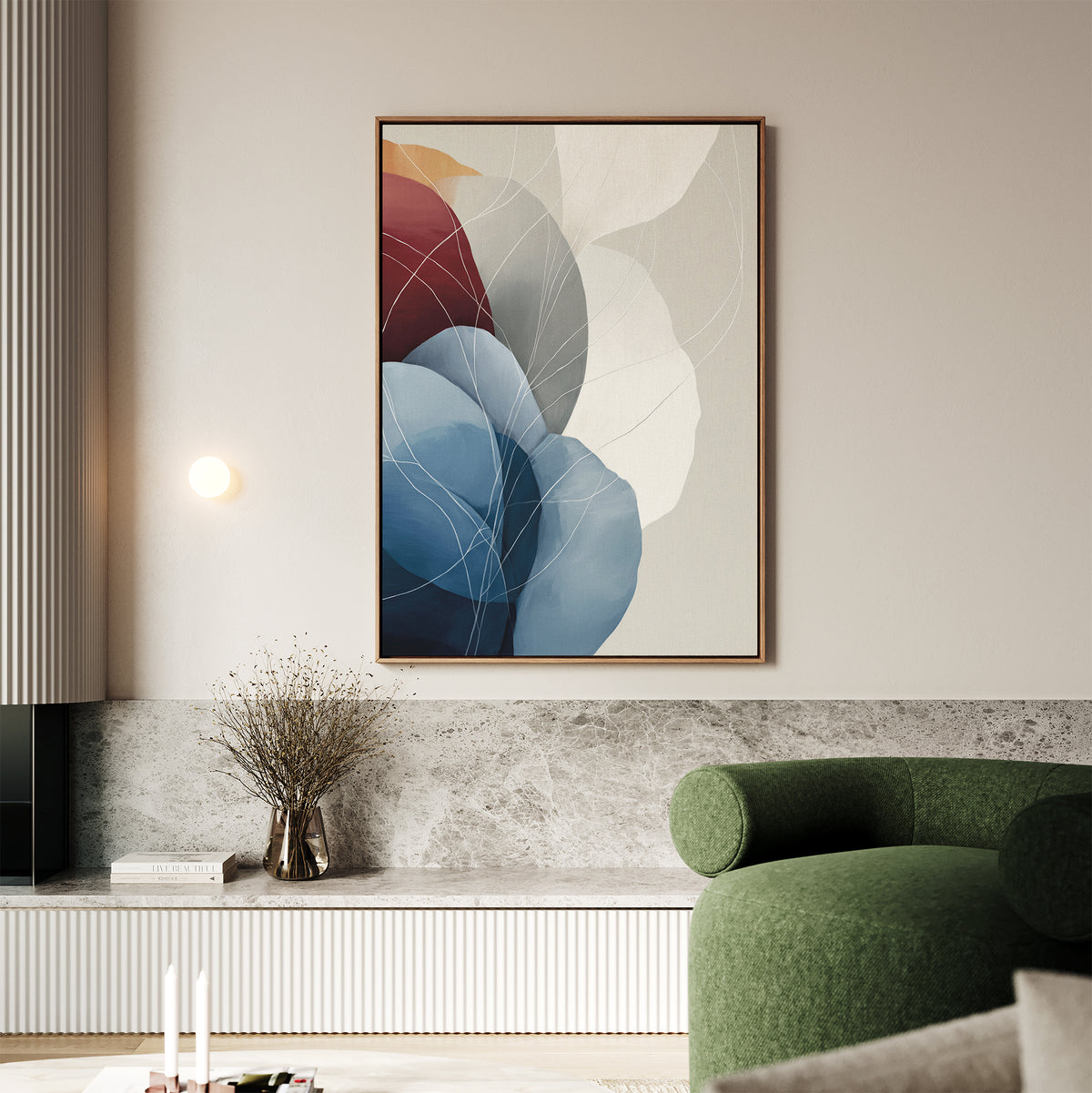 A modern living room with a green curved sofa, marble accents, a small vase with dried branches, and the Translucent Petals Canvas Art - Vertical featuring blue, red, and neutral hues on a light-colored wall.