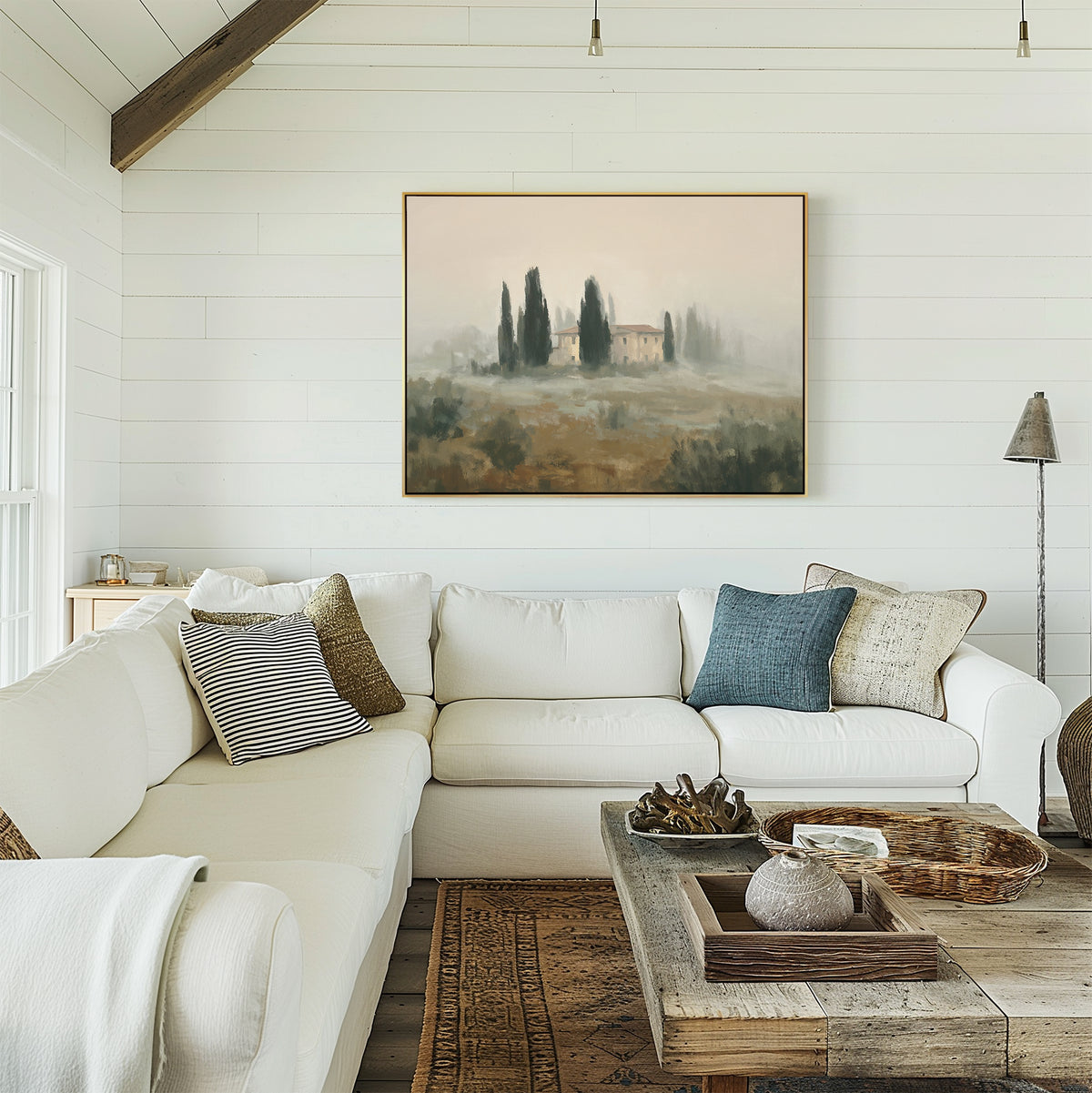 A cozy, white living room with a large sectional sofa, textured pillows, a rustic coffee table, and European wall decor featuring the Tuscan Veil Canvas Art—Horizontal. Natural light streams in from the left.