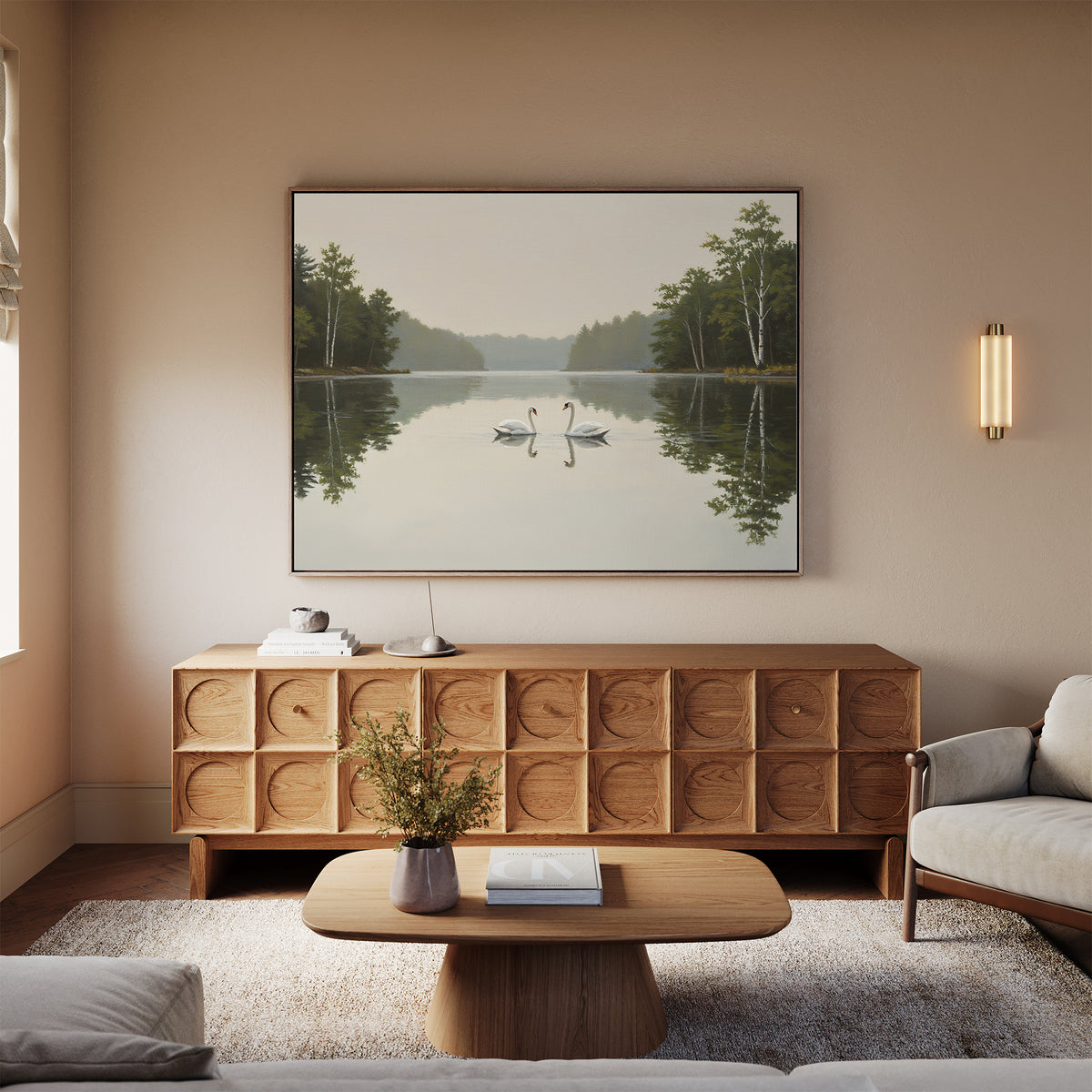 A serene living room features a light wood sideboard, coffee table, beige sofa, and the Twin Swans Serenity Canvas Art - Horizontal as Nordic Park decor. Soft lighting and neutral tones create a cozy atmosphere inspired by nature.