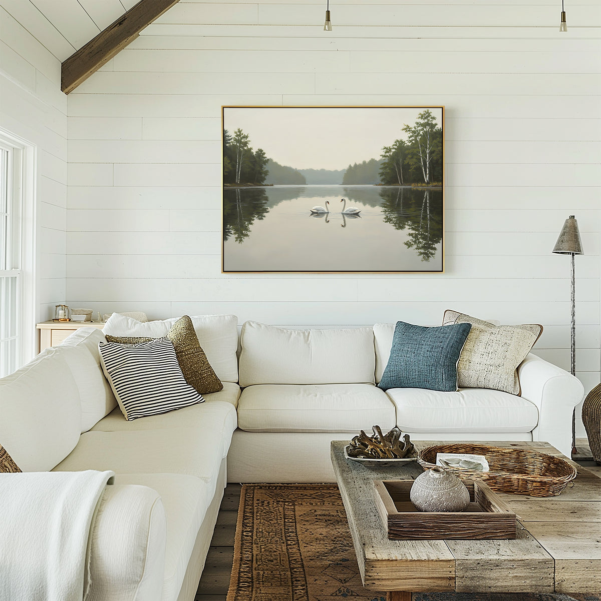 A cozy living room features a white sectional sofa, assorted pillows, a wooden coffee table, and the Twin Swans Serenity Canvas Art - Horizontal on the white shiplap wall. Natural light completes this inviting space.