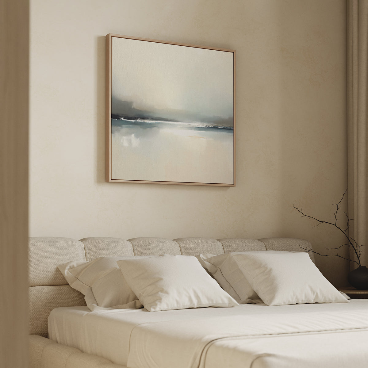 A minimal bedroom features a beige upholstered bed, white pillows, and a soft cream wall. Above the bed hangs Veiled Estuary Canvas Art - Square in muted tones with a simple wooden frame. A bare branch decorates the nightstand.