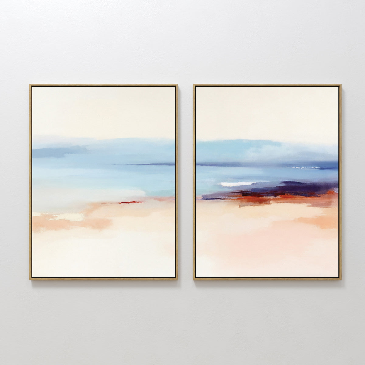 The "Windswept Coastline - Set Of 2" features framed abstract art in soft blues, beige, peach, and red accents, evoking serene Nordic coastal landscapes and creating a tranquil vibe when displayed together on a white wall.