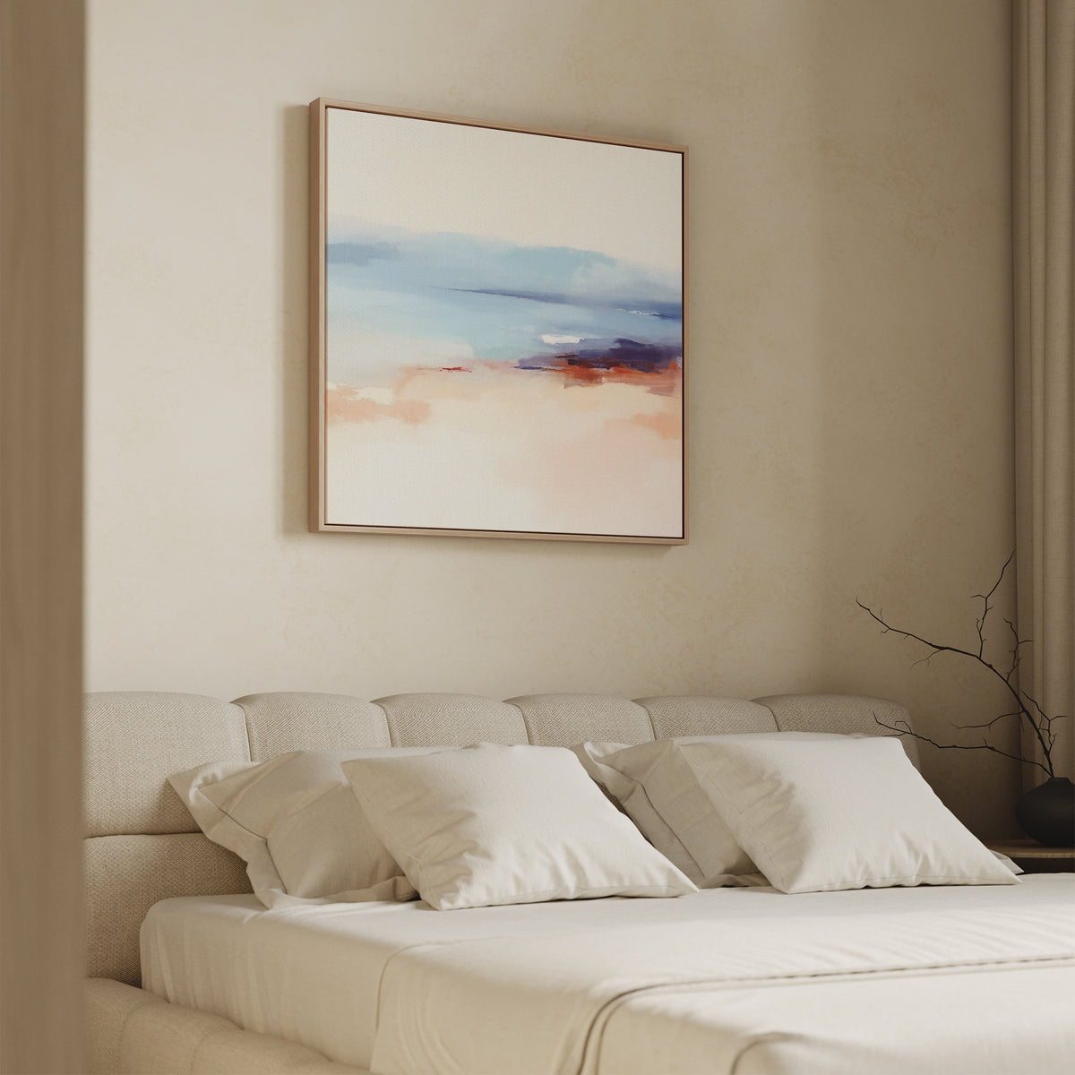 A minimalist bedroom with a beige upholstered bed, white pillows, and a soft white blanket. Above the bed hangs the Windswept Coastline Canvas Art - Square in pastel blue, pink, and orange. A bare branch decorates the side table.