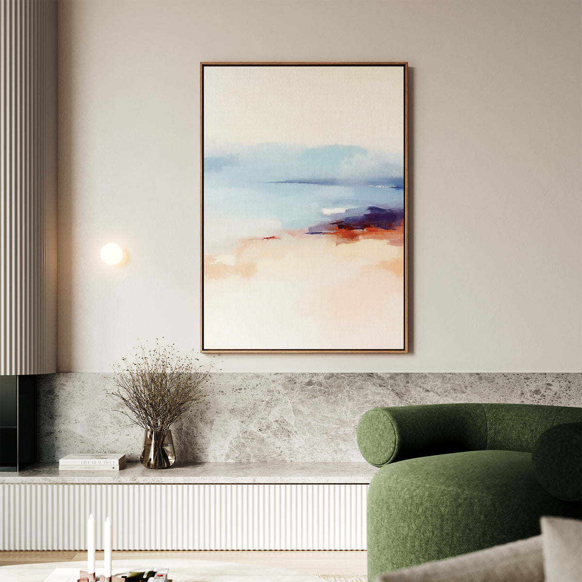 A modern living room features a green sofa, marble shelf, and a vase of dried branches. A round wall light illuminates the Windswept Coastline Canvas Art - Vertical, showcasing serene blue, peach, and purple tones on the light-colored wall.