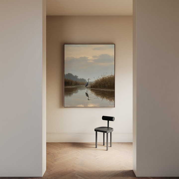 A minimalist room with light walls features a black modern chair on a wooden floor and tranquil decor—a large Misty Reflection Canvas Art depicting a heron in calm water, enhancing the neutral aesthetic of the space.
