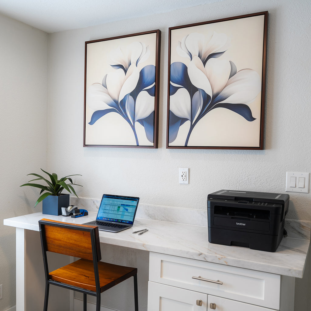A modern home office setup with a marble desk, wooden chair, laptop, printer, plant, and the Navy Magnolia Set of 2 prints as striking modern wall decor above the workspace.