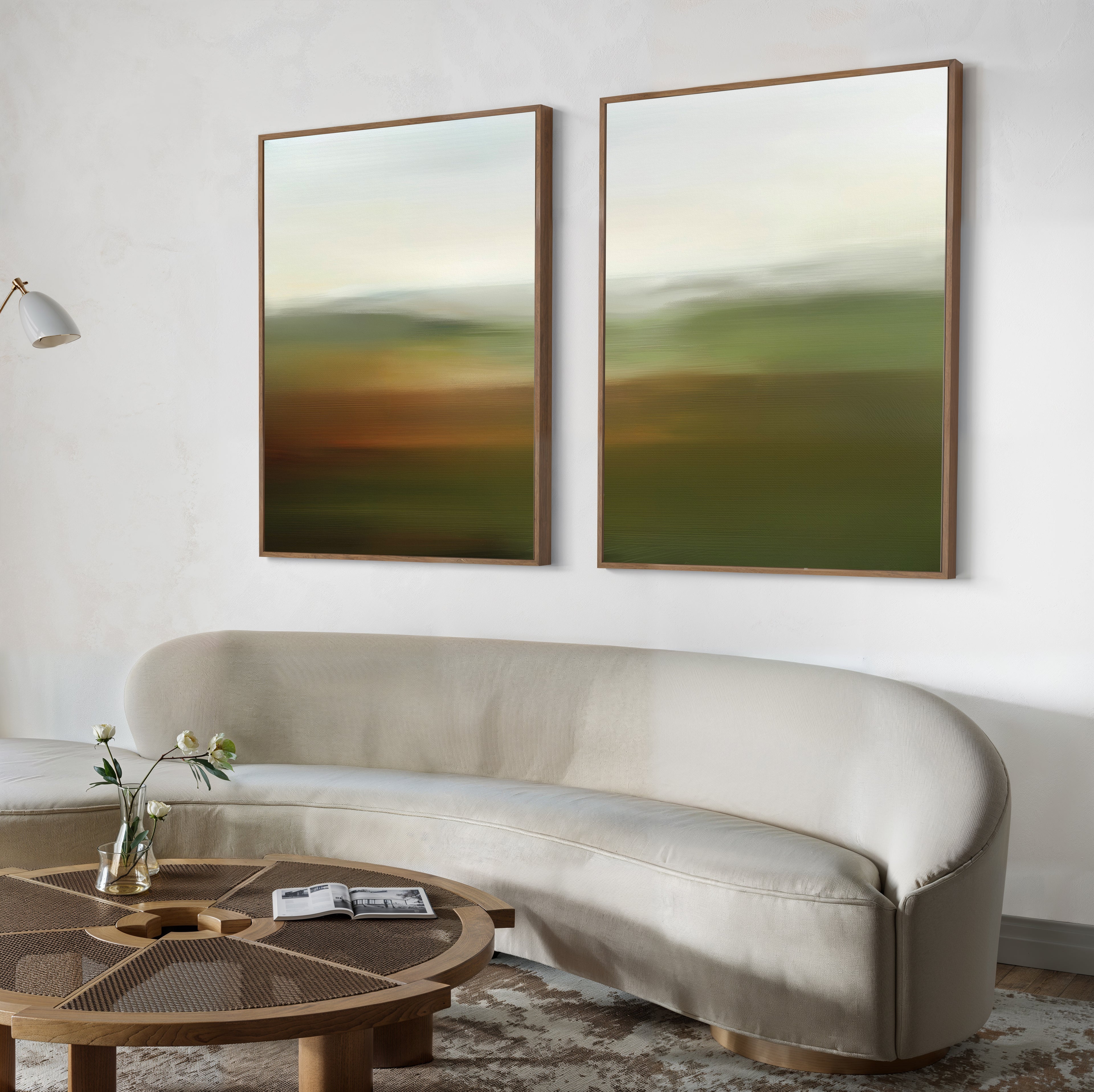 A modern living room features a curved beige sofa, a round wooden coffee table with flowers and a magazine, and the Lush Landscape Set of 2 abstract wall art prints above the sofa for stylish decor.
