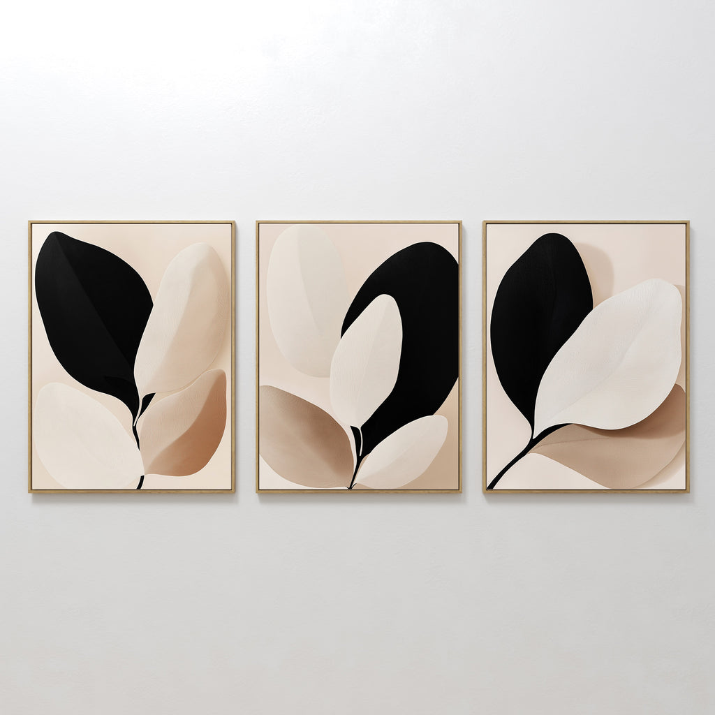 The Monochrome Flora Set of 3 features minimalist framed artworks with abstract leaf designs in black, beige, and cream—ideal for modern living rooms or as striking botanical wall art.