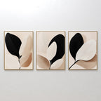 The Monochrome Flora Set of 3 features minimalist framed artworks with abstract leaf designs in black, beige, and cream—ideal for modern living rooms or as striking botanical wall art.