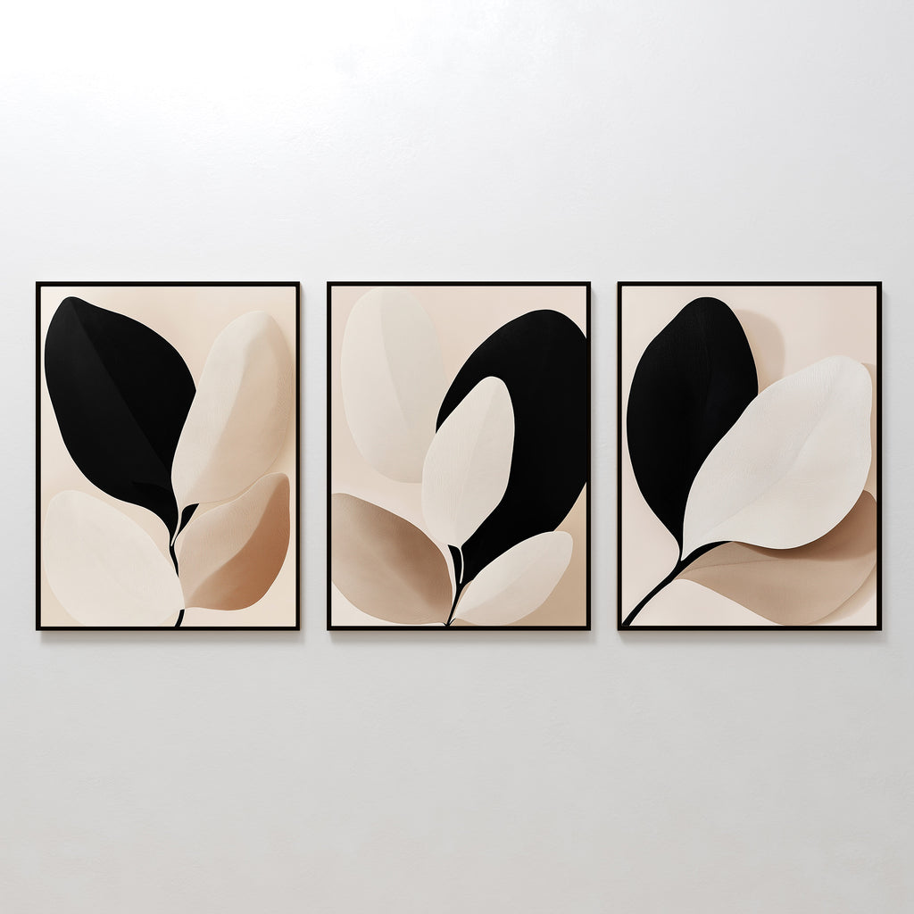 The Monochrome Flora Set of 3 features framed abstract art prints with minimalist leaf designs in black, beige, and white—perfect botanical wall art for modern living rooms, displayed together on a light-toned wall.