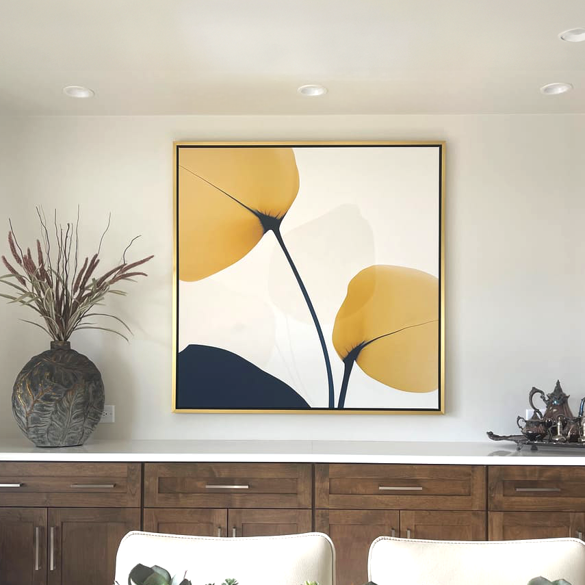 A modern kitchen features wooden cabinets, a decorative vase with dried plants, a traditional metal tea set on a white countertop, and the Golden Leaves Canvas Art with bold yellow and black shapes on the wall.