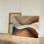 The Neutral Landscape River Abstract Canvas Art, with swirling brown and beige patterns, rests on a wooden herringbone floor against a white-paneled wall—perfect minimalist wall art for elegant living room decor. Another canvas stands blank beside it.