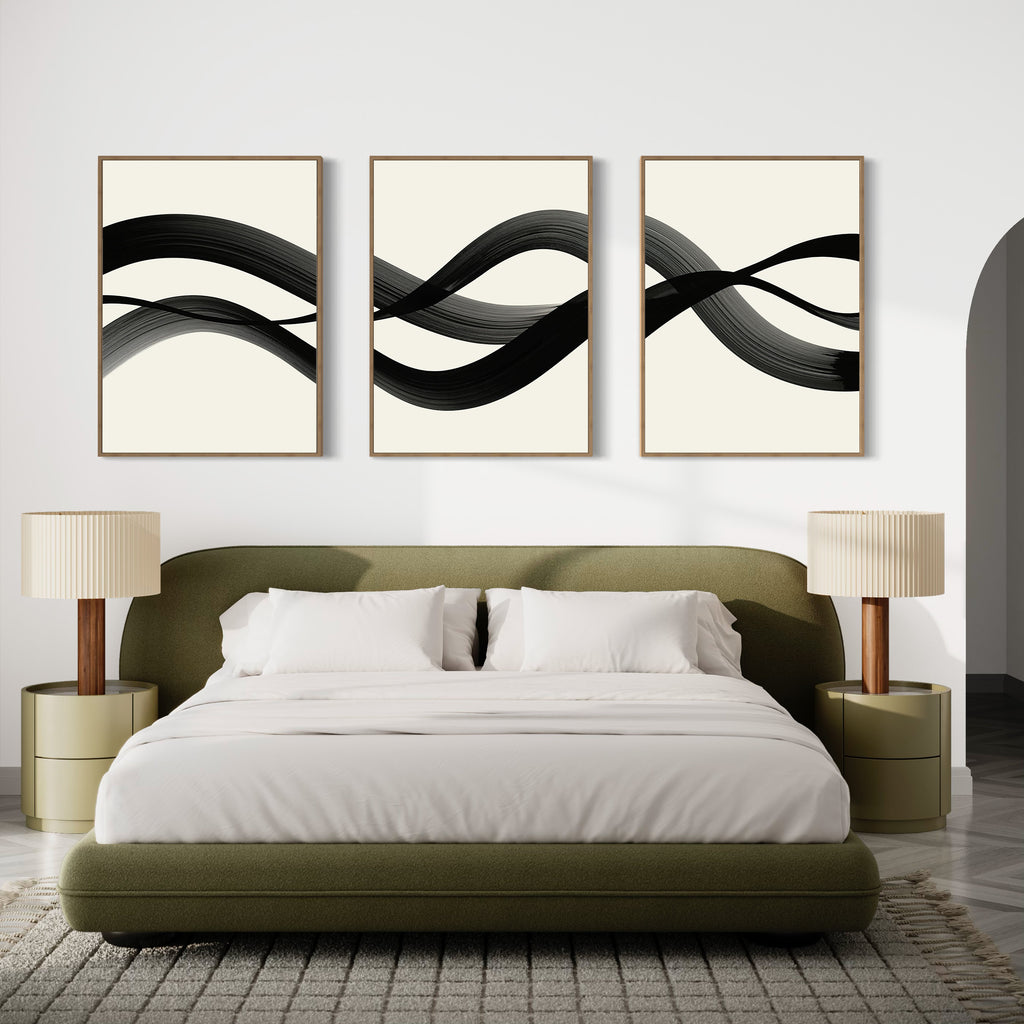 A modern bedroom features an olive green bed with white bedding, beige nightstands with matching lamps, and the Fluid Curves Set of 3 wall art above the bed, enhancing the minimalist decor and neutral palette.