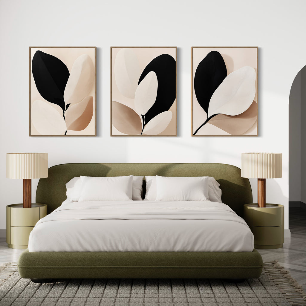 Modern bedroom with an olive green bed, white bedding, two round nightstands with beige lamps, and the Monochrome Flora Set of 3 botanical prints in neutral tones above the bed. A patterned rug covers the floor.