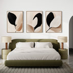 Modern bedroom with an olive green bed, white bedding, two round nightstands with beige lamps, and the Monochrome Flora Set of 3 botanical prints in neutral tones above the bed. A patterned rug covers the floor.