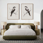 A modern bedroom with a green upholstered bed, neutral bedding, two round nightstands and lamps, plus striking Still Perch Set of 2 bird art prints from Nordic Park displayed above the headboard.