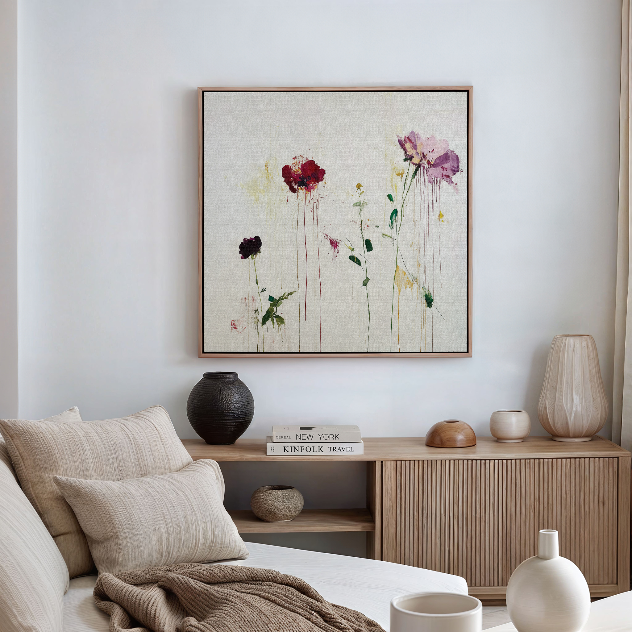 A cozy, modern living room features a light sofa, neutral cushions, wooden sideboard, decorative vases, books, and the Wild Flower Canvas Art—a large painting of red and pink flowers that brightens the white wall.