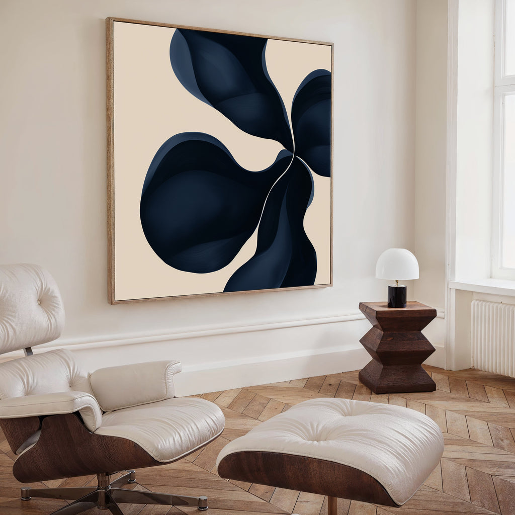 A modern living room with a cream lounge chair and ottoman, dark wooden side table, white lamp, and Blossom Blue Abstract Canvas Art featuring navy and beige above the seating area.