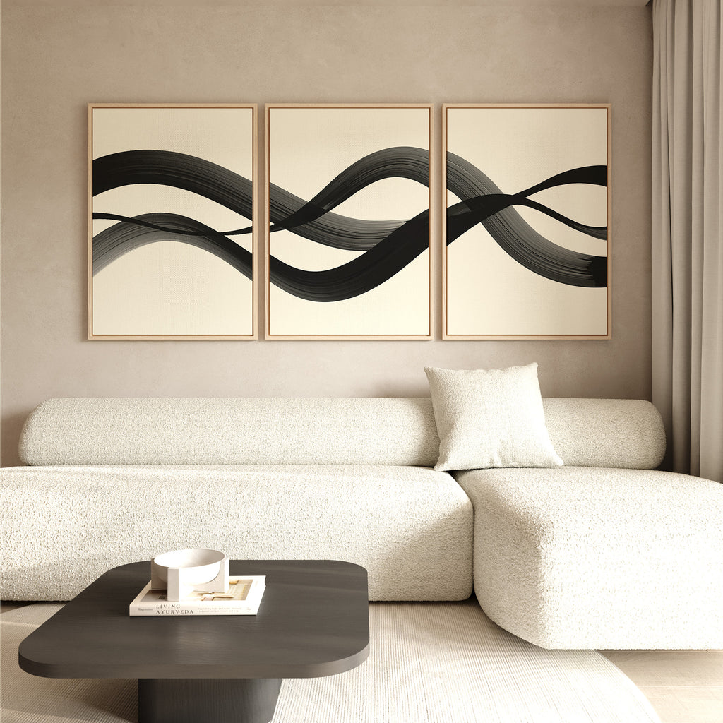 Minimalist living room featuring a light textured sofa with single cushion, dark coffee table, and Fluid Curves Set of 3 wall art above the couch. Soft neutral tones and natural light create a calm, Nordic Park-inspired vibe.