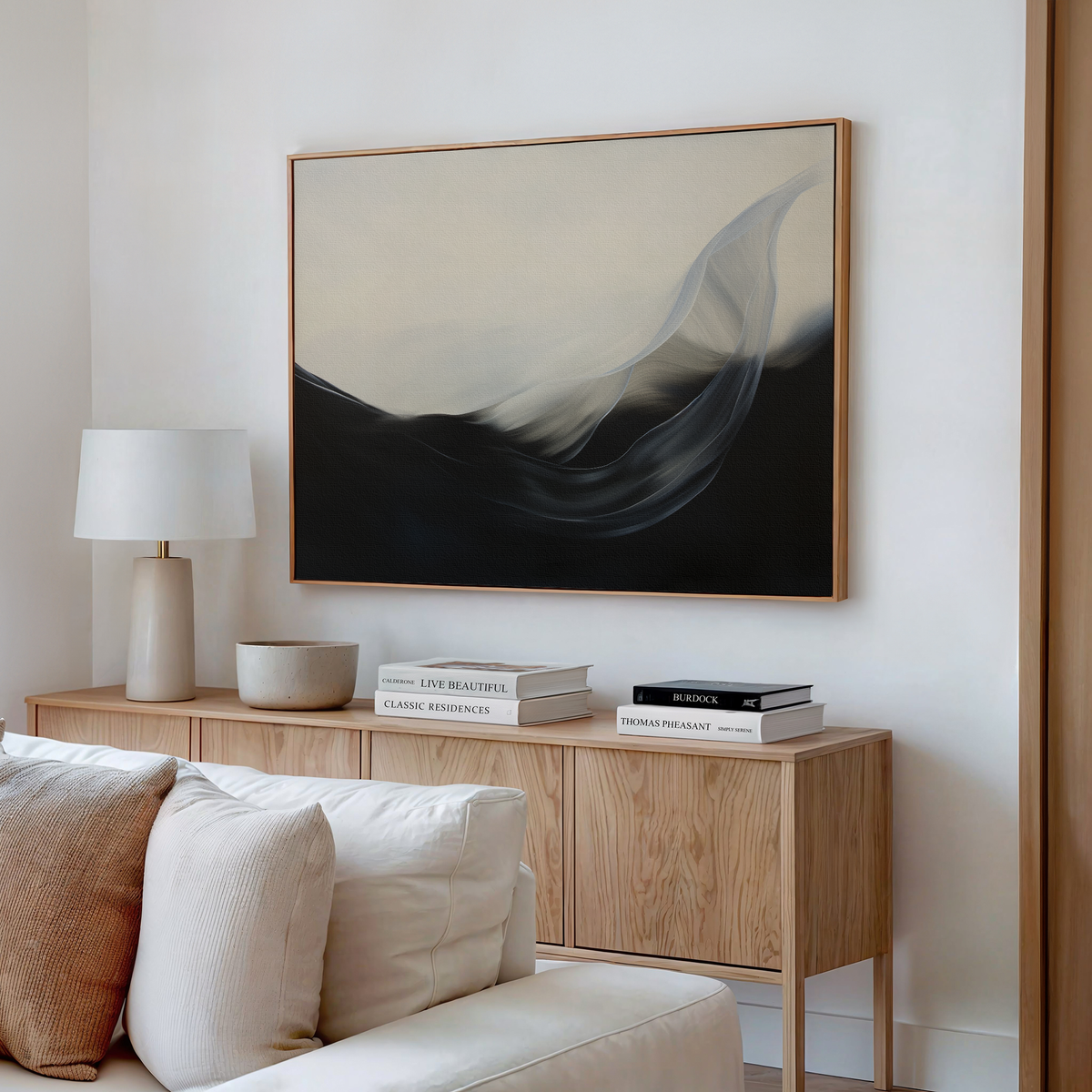 A modern living room with a wooden sideboard, table lamp, books, decorative bowl, and the Oceanic Pulse Abstract Canvas Art featuring dark and light waves above a light sofa—perfect for stylish living room decor.