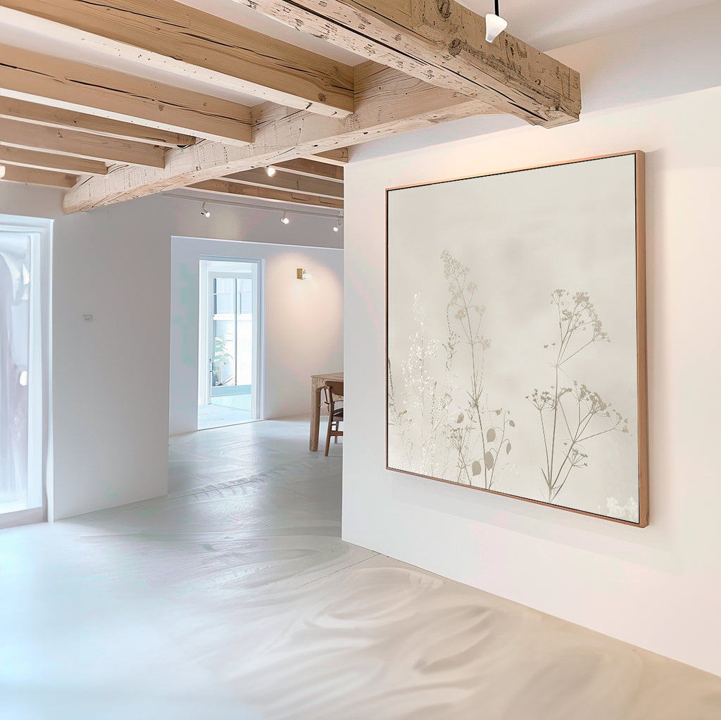 A minimal, modern room with light wood ceiling beams and white walls features the Floral Symphony Abstract Canvas Art with delicate botanical silhouettes. Natural light pours in through windows and a door, brightening the living room decor.