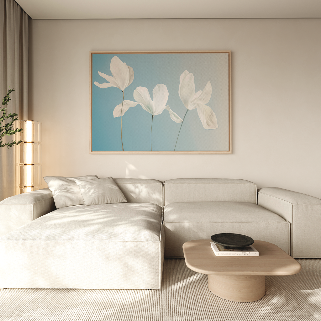 A modern living room with a light beige sectional, low round wooden coffee table, neutral walls, and large Stellar Flora Abstract Canvas Art featuring white petals on blue—perfect for stylish living room decor.