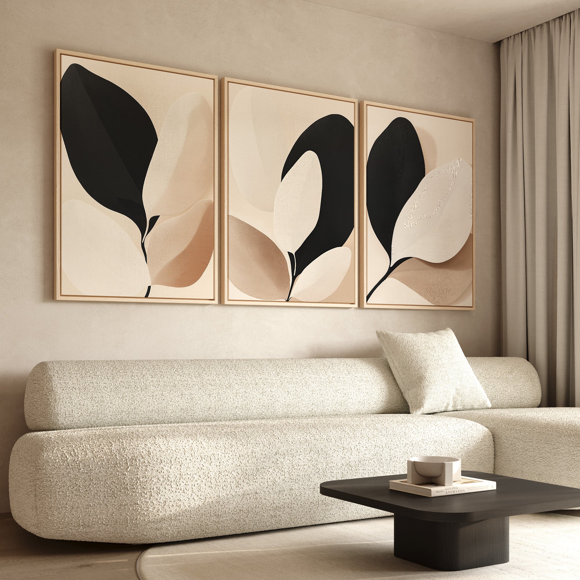 A modern living room features a textured beige sofa with matching pillow, a low black coffee table with cup and book, and the Monochrome Flora Set of 3 abstract botanical wall art in neutral tones above, complemented by light curtains.