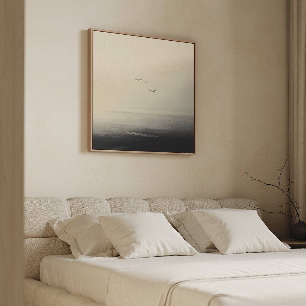 A minimalist bedroom showcases the Above the Calm Canvas Art above a beige bed with white pillows, depicting flying birds. A simple vase with bare branches completes the serene decor.