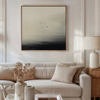 A modern living room with a beige sofa, neutral cushions, a side table with a cream lamp, and minimalist wall art—Above the Calm Canvas Art featuring three birds flying over a misty sea—perfect for large living room decor.