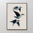 Abstract Birds in Motion Canvas Art features three minimalist, abstract birds in blue and beige on a light background. Framed in black, this modern wall art print is displayed on a white wall.