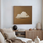 A minimalist living room features a beige couch with striped cushions, a light wood sideboard with vases and books, and modern wall art—Amber Sky Cloud Canvas Art, a framed painting of a white cloud on a brown background—above.
