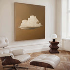 A minimalist living room with a white lounge chair and ottoman, wood floors, a geometric wood side table with a small lamp, and the Amber Sky Cloud Canvas Art featuring a white cloud on brown hanging on the wall.