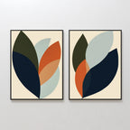 The Autumn Layers Set of 2 features framed abstract wall art prints with overlapping leaf-like shapes in dark blue, olive green, light blue, and orange on a cream background—ideal for enhancing living room decor when displayed together.