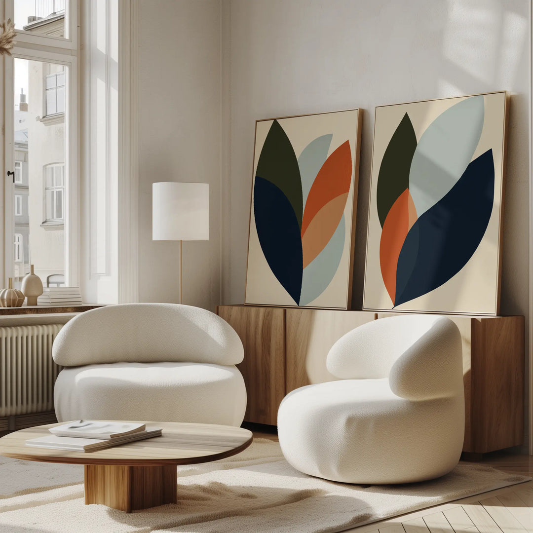 Modern living room featuring the Autumn Layers Set of 2 rounded white armchairs, a low wooden coffee table, floor lamp, and abstract wall art on a wooden sideboard. Sunlight through tall windows highlights the stylish decor.