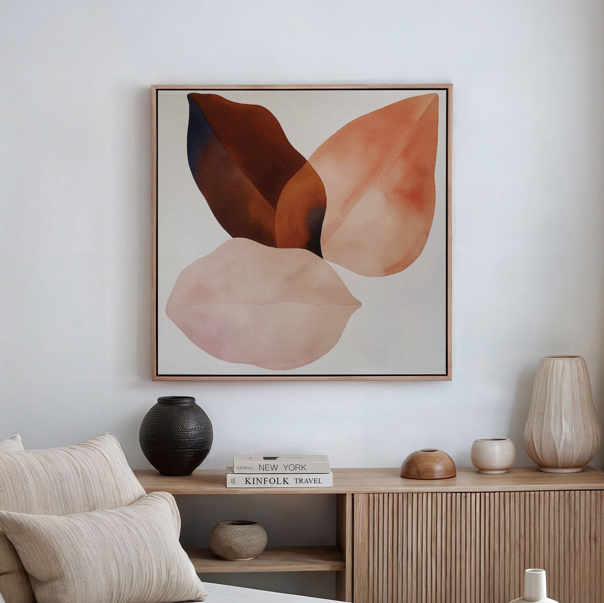 A minimalist living room showcases a beige couch, pale cushions, a light wood sideboard with neutral vases and books, and Autumn Petals Canvas Art in earthy tones on a white wall.