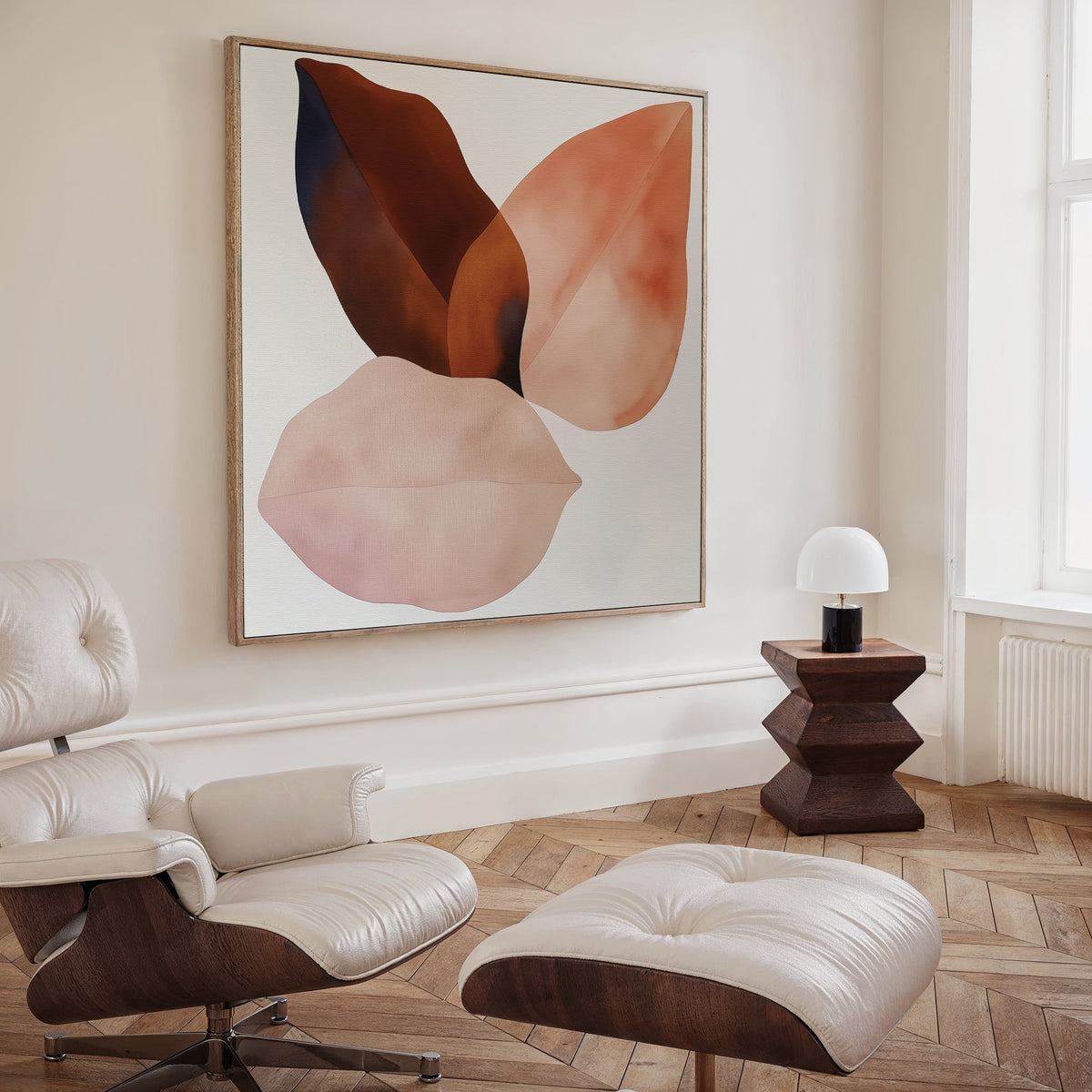 A modern living room with wooden herringbone floors, a white leather lounge chair and ottoman, a geometric wooden side table with a small white lamp, and striking Autumn Petals Canvas Art featuring abstract earthy-toned leaf shapes.