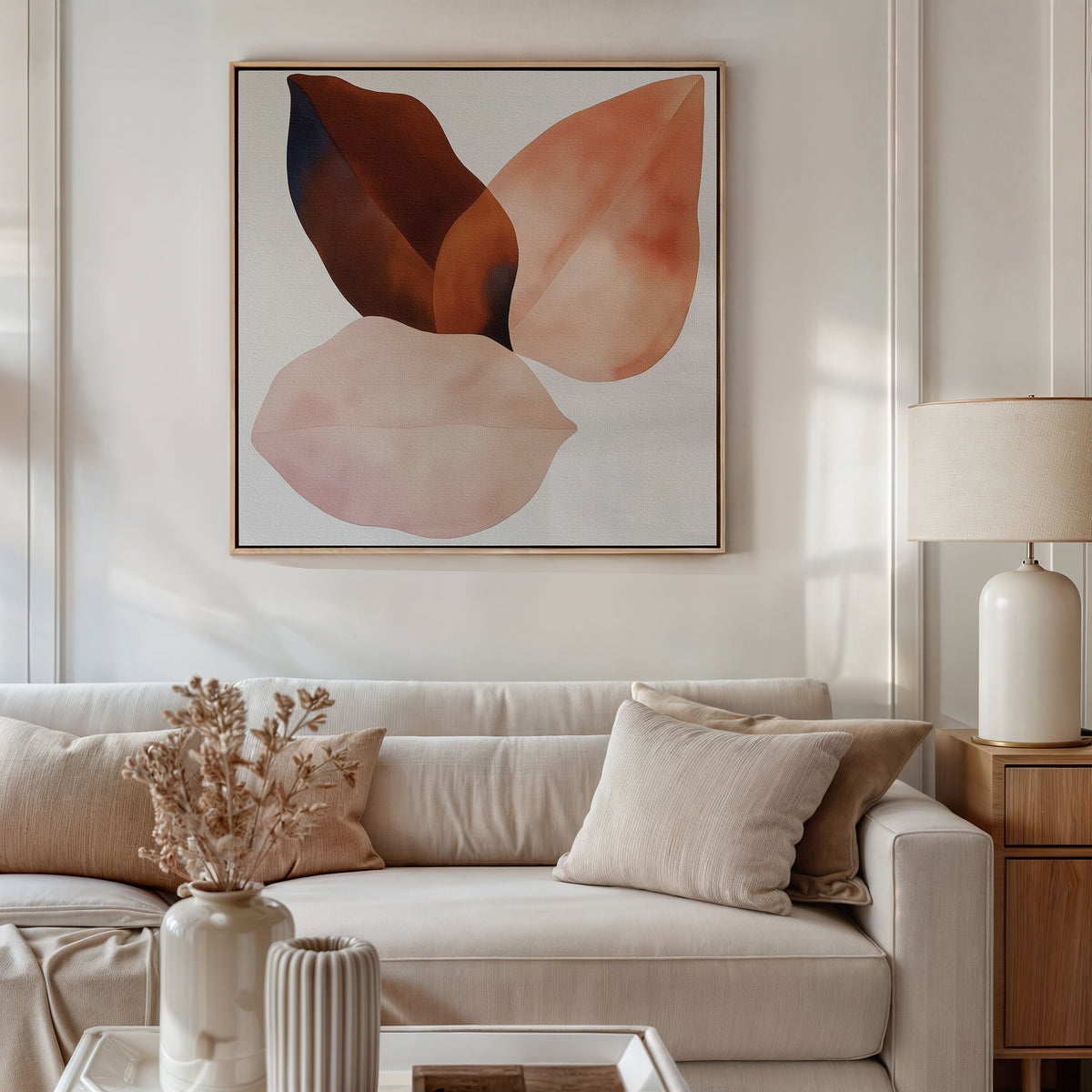 A modern living room features a beige sofa, neutral pillows, white table, dried flowers in a vase, and the Autumn Petals Canvas Art in soft brown and pink tones above the sofa. A table lamp rests on a wooden side table.