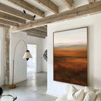 A modern living room with exposed wooden beams, white walls, and the Autumn Plains Abstract Canvas Art in warm earth tones above a white sofa. A curved floor lamp adds elegance while natural light flows in from adjoining rooms.